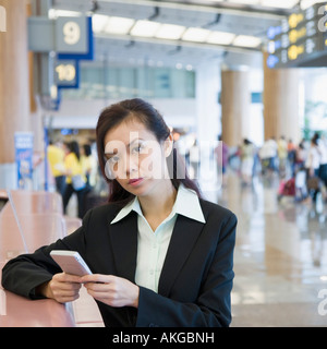 Porträt von eine Geschäftsfrau mit einer Hand gehalten Gerät an einem Flughafen Stockfoto