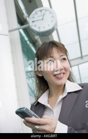 Niedrigen Winkel Blick auf eine Geschäftsfrau hält ein Mobiltelefon und wartet an einer Flughafen-lounge Stockfoto