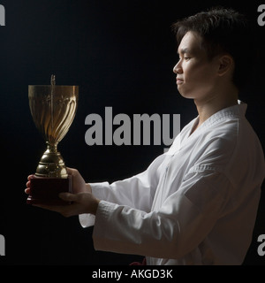 Seitenansicht eines jungen Mannes hält eine Trophäe Stockfoto