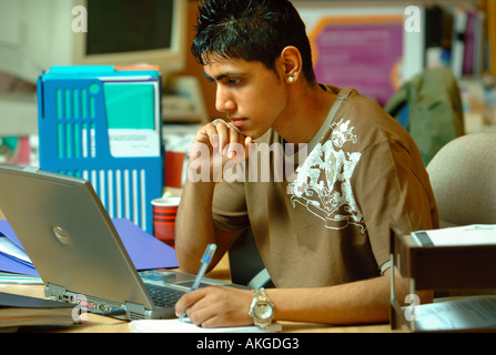 EIN TEENAGER ARBEITET AN EINEM LAPTOP-COMPUTER IN EIN OFFICE-UMGEBUNG-UK Stockfoto