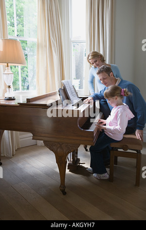 Eltern mit Tochter spielt Klavier Stockfoto