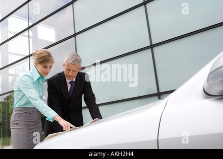 Geschäftsfrau und Geschäftsmann Blick auf Karte auf Kfz Motorhaube Stockfoto