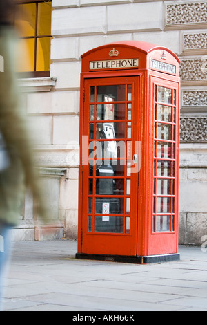 Frau zu Fuß vorbei an eine legendäre rote Telefonzelle in London.  Canon "L" Objektiv. Stockfoto