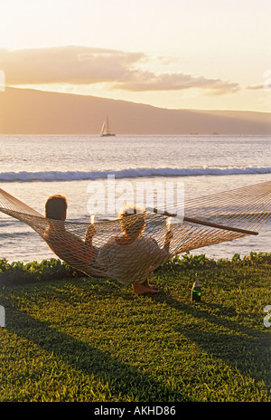 Paar sitzt in Hängematte Sonnenuntergang Flasche Champagner feiert das gute Leben auf der Insel Maui Stockfoto
