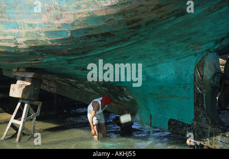 Mann, die Reparatur ein hölzernes Fischerboot in den Hafen von Essaouira, Marokko, Nordafrika Stockfoto