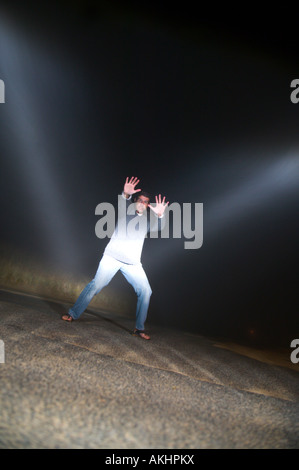 Mann im Pfad des entgegenkommenden Autos in der Nacht Stockfoto