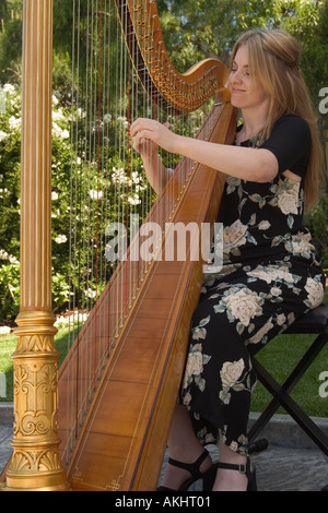 Eine weibliche Harfenistin spielt die Harfe auf einer Gartenparty Stockfoto
