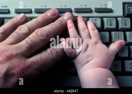 Baby s Hand und Mann s auf Computer-Tastatur Stockfoto