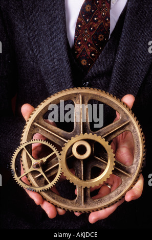 Ein Geschäftsmann mit Messing-Zahnräder in den Händen Stockfoto