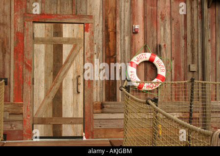 Ein Wasser-Bouey hängen neben einer Tür ein Gebäude mit roten abgenutzte Holz Abstellgleis entlang der Docks Stockfoto