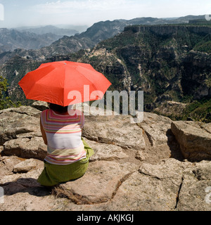 Frau Suche heraus auf Copper Canyon Gebirge Holding orange rot Sonnenschirm Regenschirm Schatten Stockfoto