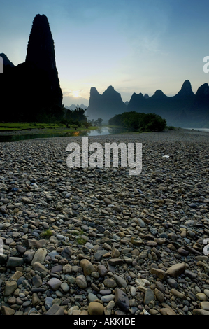 Blick über das steinige Ufer des Li Jiang-Fluss bis zu den Berggipfeln Kalkstein Xinping bis Yangshuo, China. Stockfoto