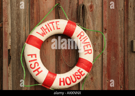Ein Wasser Bouey hängen eine rote getragen Wald(Holz) Abstellgleis auf einem Gebäude entlang der Docks Stockfoto