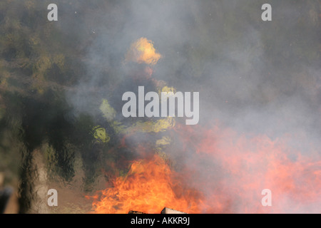 Ein Feuerwehrmann in der Hitze, die Resonanz aus dem Feuer an einem Einsatzort mit Asche in die Luft fliegen Stockfoto