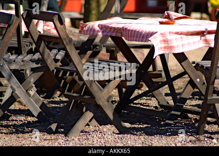 Café im Freien im Frühjahr mit Holzmöbeln und aufgegebenen Tischdecken in rot und weiß Stockfoto
