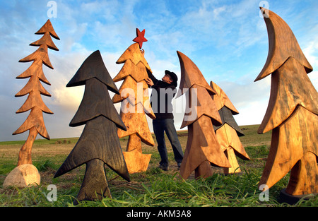 Künstler Johnny Woodford mit seiner surrealen Weihnachtsbäume aus Holz geschnitzt mit einer Kettensäge. Stockfoto