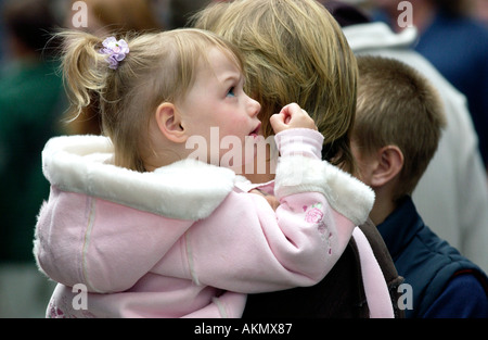 Junge Mädchen in Mütter Arme nachschlagen in der Markthalle die jährlichen Food Festival in Abergavenny Monmouthshire Wales UK GB Stockfoto