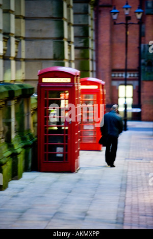 2 rote Telefonzellen mit Mann vorbeigehen. Birmingham. Vereinigtes Königreich. Stockfoto