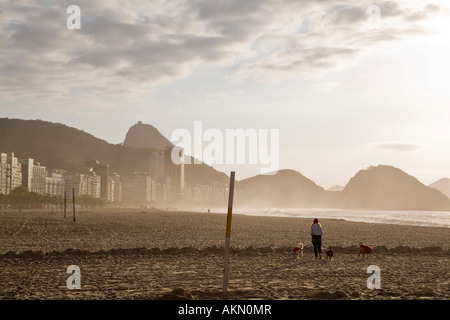 Copacabana-Strand in den frühen Morgenstunden Rio De Janeiro Brasilien Frau macht einen Spaziergang mit ihren 3 Hunden Stockfoto