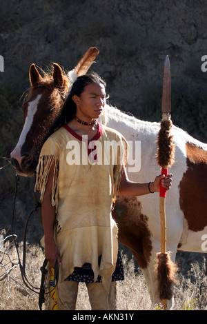 Ein Native American Indian-junge trägt eine Feder stand neben einem Pferd hält einen Speer mit Buffalo ausblenden drauf Stockfoto