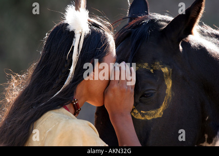 Ein Native American Indian-junge trägt eine Feder spricht mit seinem Pferd gemeinsam einen besonderen Moment wie ein Pferdeflüsterer Stockfoto