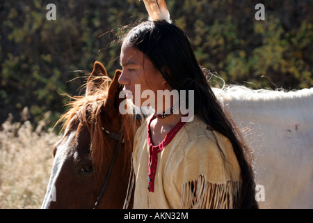 Ein Native American Indian-junge trägt eine Feder stand neben einem Pferd Stockfoto