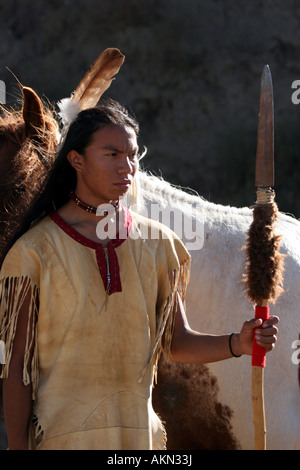 Ein Native American Indian-junge trägt eine Feder stand neben einem Pferd hält einen Speer mit Buffalo ausblenden drauf Stockfoto