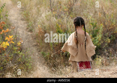 Ein junger, Native American Indian Boy in Zöpfen zu Fuß, nach unten einen Pfad mit einem Stück Rasen Stockfoto