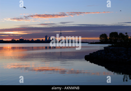 Rote Wolken über der Skyline von Toronto in der Morgendämmerung spiegelt sich in Humber Bay Park Lake Ontario Stockfoto