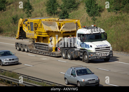 Verkehr vorbei langsam fahrenden SCANIA Bonnet LKW Smiths Schwertransport Tieflader Anhänger große Maschinenladung Fahren entlang Autobahn England Großbritannien Stockfoto