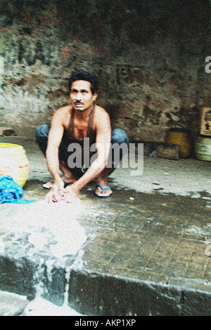 Ein Mann wäscht seine Kleider am Straßenrand in Kolkatta, West Bengal, Indien. Stockfoto