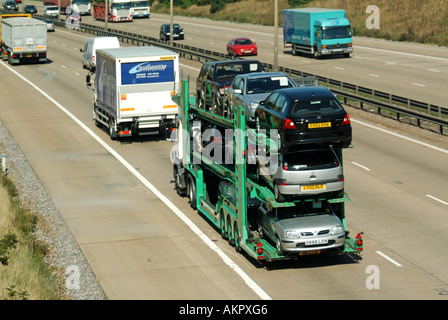 Autotransporter LKW-Anhänger im Verkehr entlang fahren auf dreispurigen Beton Autobahn Straße Oberfläche mit harten Schulter & Stahl Crash Barriere UK Stockfoto