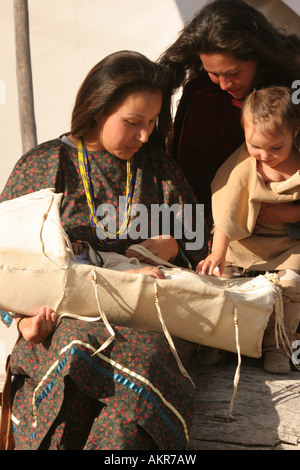 Junge Frau mit ihrem Baby in einer Wiege und eine andere Mutter und ihr Babymädchen besuchen Native American Indian Stockfoto