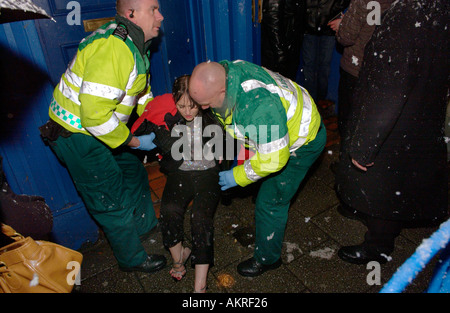 Sanitäter, die Teilnahme an einer jungen Frau, die hat gefallen und verletzten Knöchel während eines Schneesturms auf eine Nacht in Cardiff Stockfoto