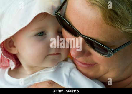 Großmutter und Enkelkind Baby von 8 Monaten mit Sonnenhut und eine Frau im Alter von etwa 45 bis 55 Jahren mit Sonnenbrille Stockfoto