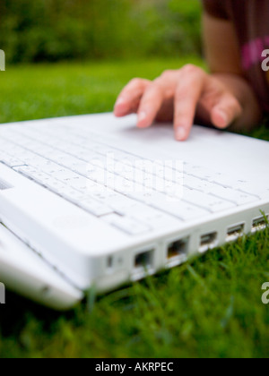 Weibliche Hände mit einem weißen Laptop im Freien auf einer Wiese Stockfoto
