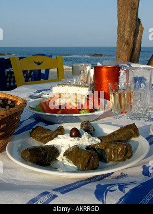 Typisches griechisches Essen Tsatsiki Tsaziki Tzatziki Doladakia gefüllt Blätter der Rebe griechischer Salat Wein auf einem Tisch am Strand von Sarti Stockfoto
