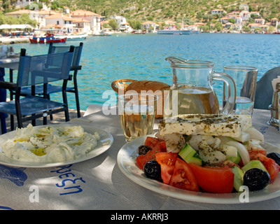 griechischer Salat Tsatsiki Krug gefüllt mit weißen Wein-Korb mit Brot auf einem Tisch im Hintergrund Türkis farbigen Mittelmeer Stockfoto