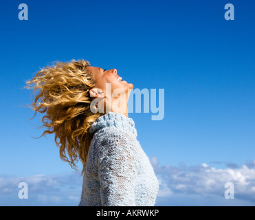 Seitenansicht der hübsche Frau halten Kopf wieder lächelnd mit wehenden Haaren Stockfoto