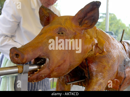 ein ganzes Schwein braten auf einem Grill Spieß mit Koch Stockfoto