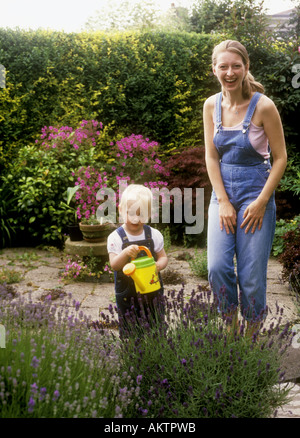 Kleinkind alt mit ihrer Mutter mit einer Gießkanne, Lavendel Pflanzen im Garten Wasser Stockfoto