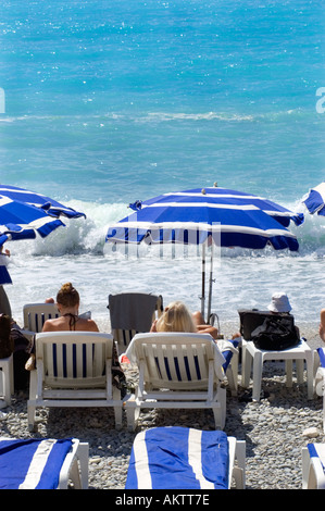 Nizza Frankreich, "Strandszene" "Mitte Erwachsene Frauen" "Zum Sonnenbaden am Strand" Regenschirme in der Nähe von Wasser 'Mittelmeer' 'Lounge Stühle" Stockfoto