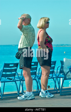 Schönes Frankreich, Strandszene, Paar mittleren Alters in der Nähe des Wassers in Shorts und Sneakers, 'zurück an zurück' im Profil über Urlaub, französische riviera Frau Stockfoto