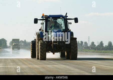 Traktor Besprühen mit Wasser um den Staub auf einer neuen Umgehungsstraße zu halten. Stockfoto