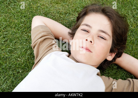 Pre-teen Boy auf Rücken Gras, die Hände hinter Kopf, erhöhte Ansicht Stockfoto