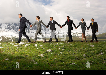 Business People Holding Hands und Walking durch Berge, Seitenansicht Stockfoto