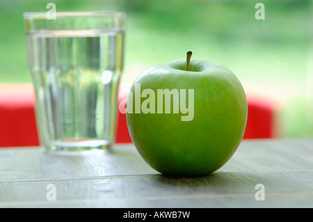 Grüner Apfel, neben einem Glas Wasser, Nahaufnahme Stockfoto