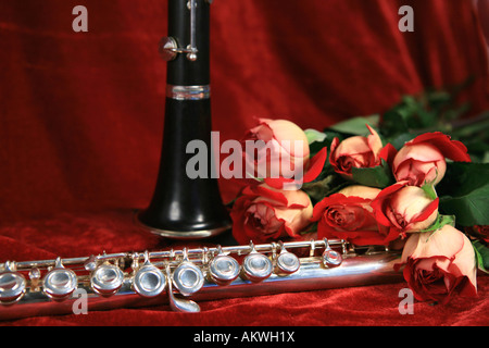 Querflöte und Klarinette mit Bouquet Rose auf rotem Samt Hintergrund Stockfoto