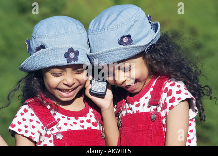 Zwillingsschwestern telefonieren mit Handy Stockfoto