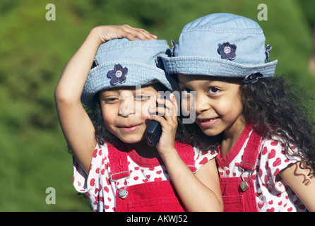 Zwillingsschwestern telefonieren mit Handy Stockfoto